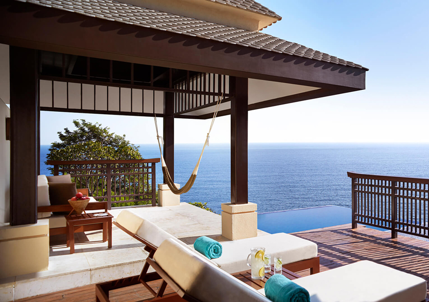 Cabo Marques | A serene patio overlooks the sea, with a lounging area featuring cushions and a wooden railing.