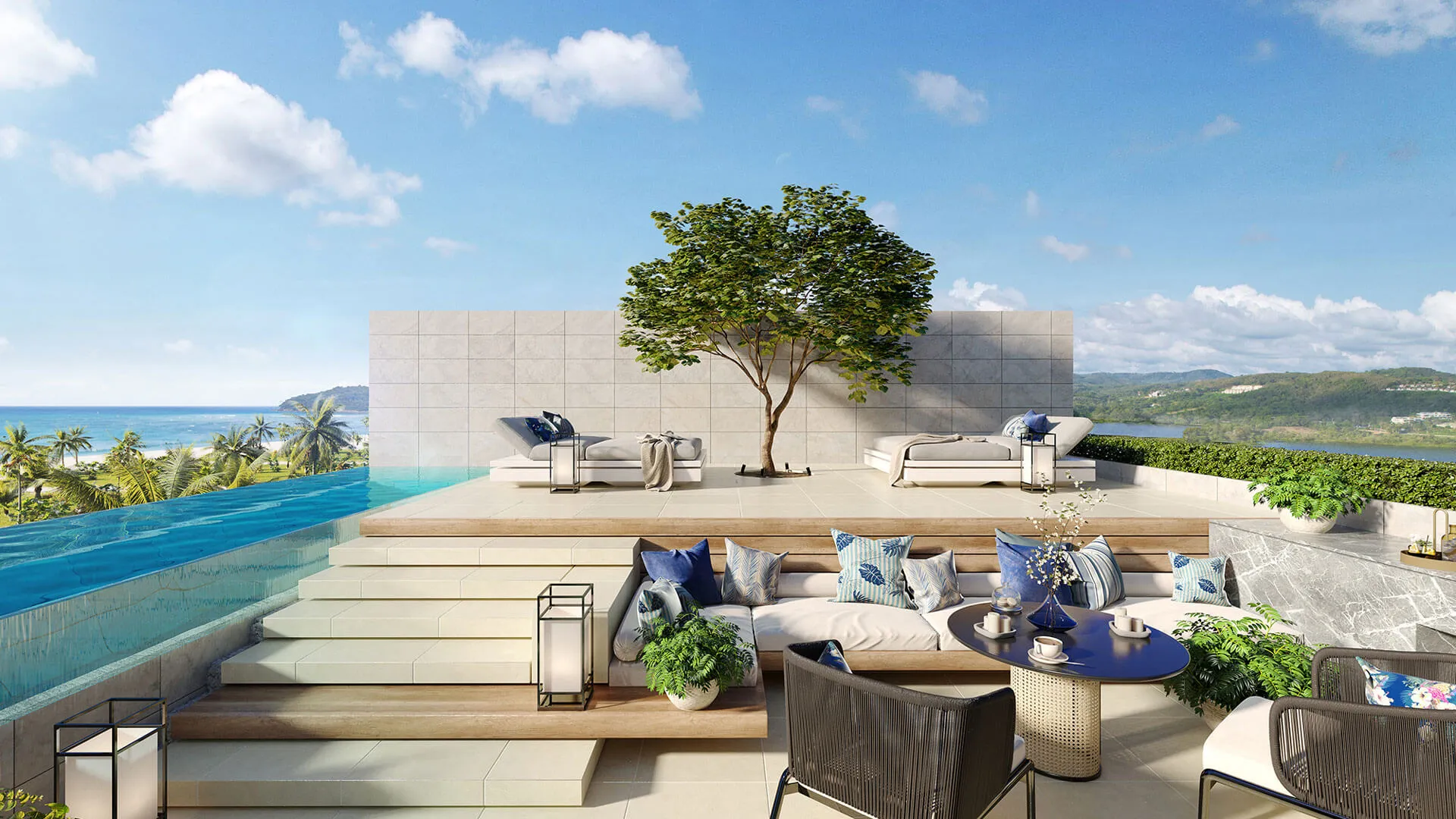 A luxurious terrace with lounge chairs, a tree, and an infinity pool overlooking a tropical beach with palm trees and hills in the distance.