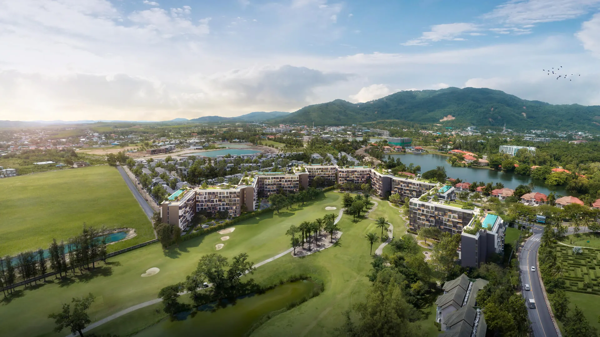 Skypark Celeste | An aerial view of a golf course surrounded by modern residential buildings, with a lake, roads, and distant mountains under a partly cloudy sky.