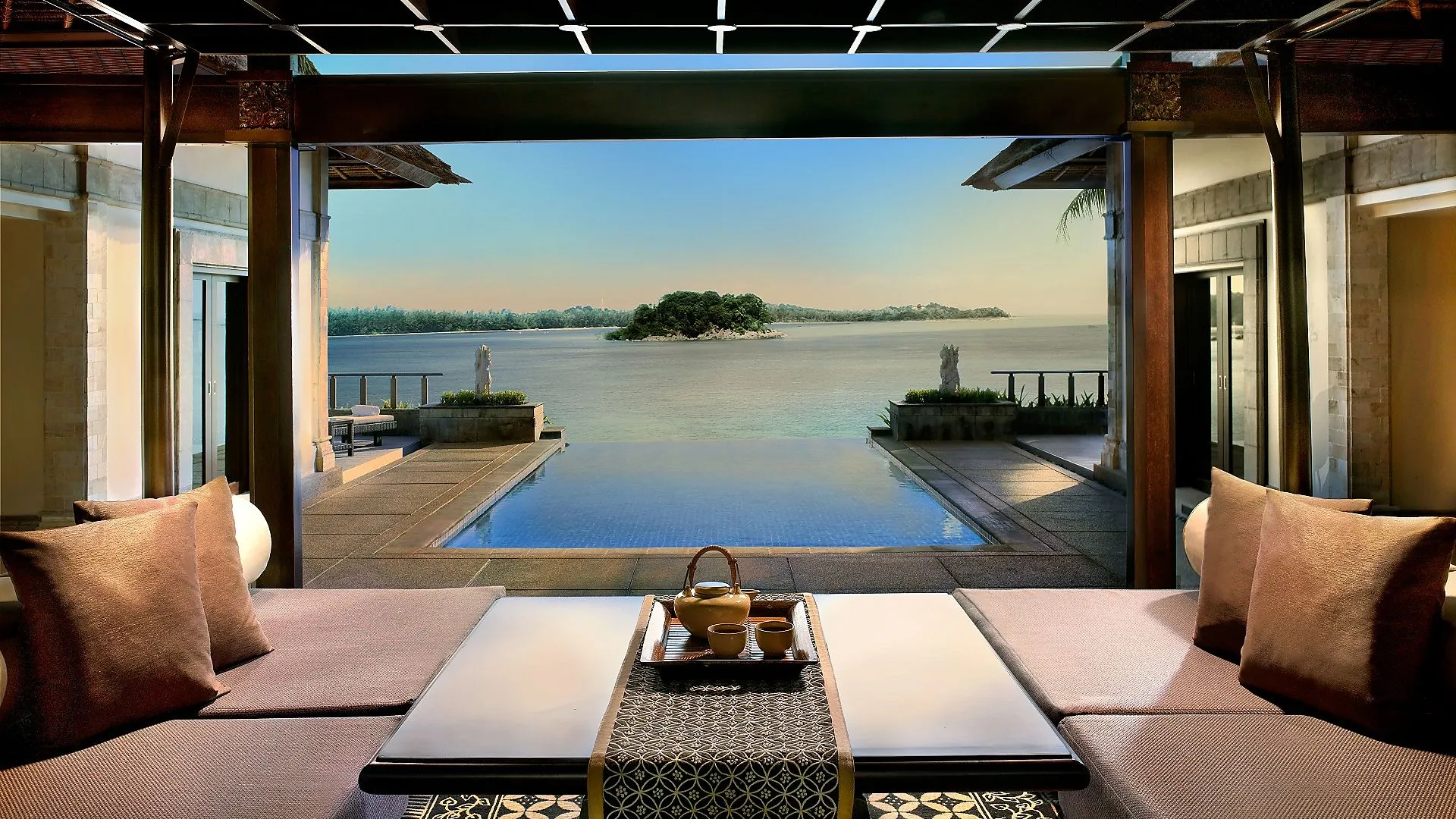 Banyan Tree Residences Bintan | outdoor dining setup overlooks an infinity pool blending into a tranquil river with an island.