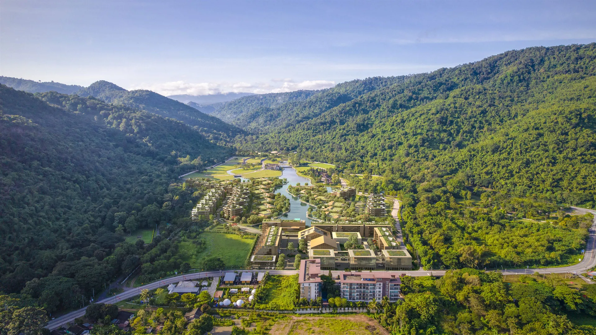 Banyan Tree Residences Creston Hill - Aerial view of a lush green valley with staggered residential structures near a winding river.