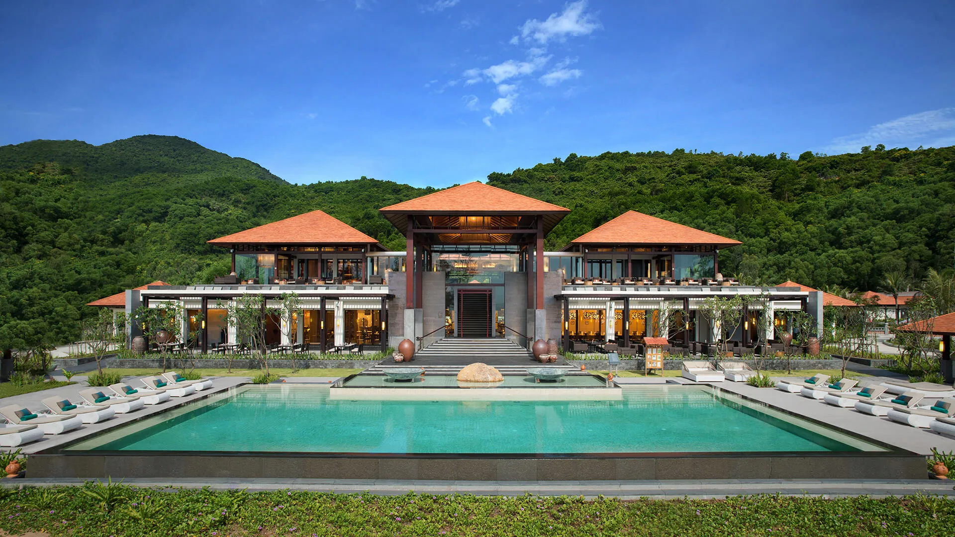 Banyan Tree Residences Lăng Cô - A luxurious resort with a symmetrically designed swimming pool in the foreground and multiple buildings with red-tiled roofs.